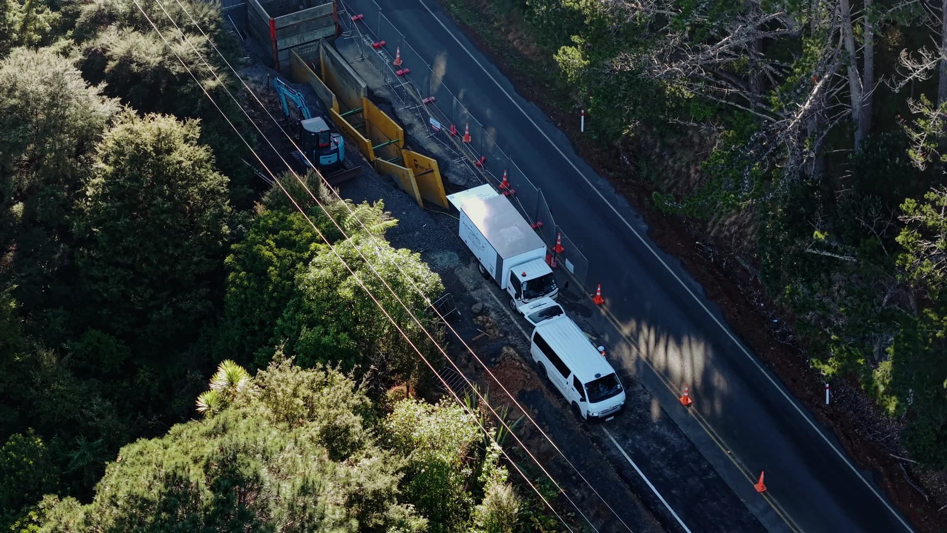Roadside job in the bush from above, truck and van beside the trench shoring